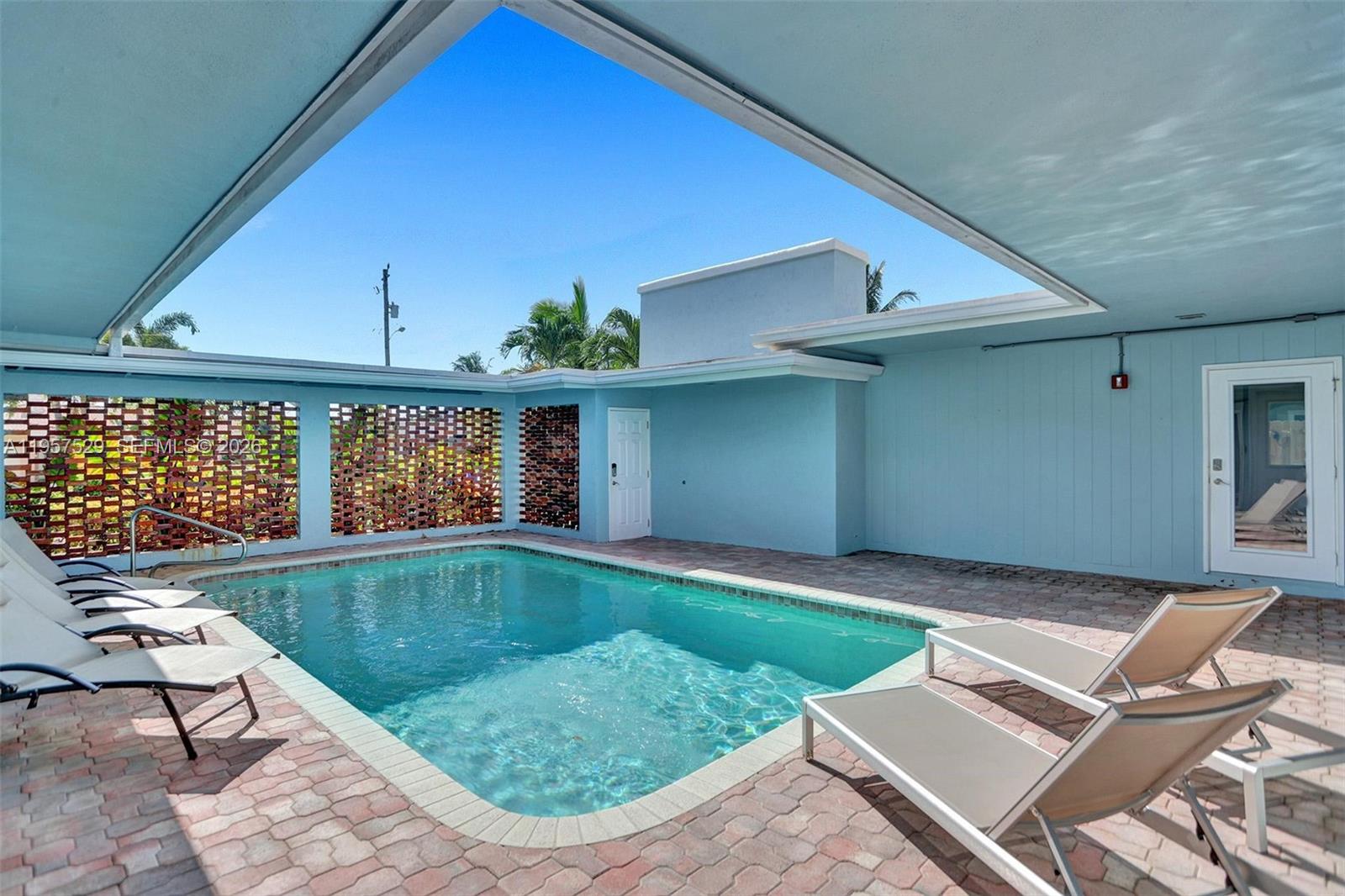 A rectangular swimming pool sits on a brick patio beneath a large, open-air roof cutout — 1341 SE 7th Ave, Pompano Beach FL 33060, POMPANO BEACH, FL