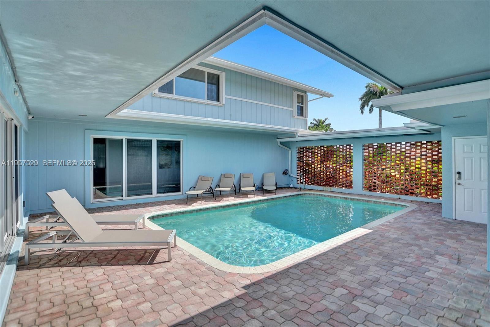 A swimming pool sits on a brick patio surrounded by light blue exterior walls — 1341 SE 7th Ave, Pompano Beach FL 33060, POMPANO BEACH, FL