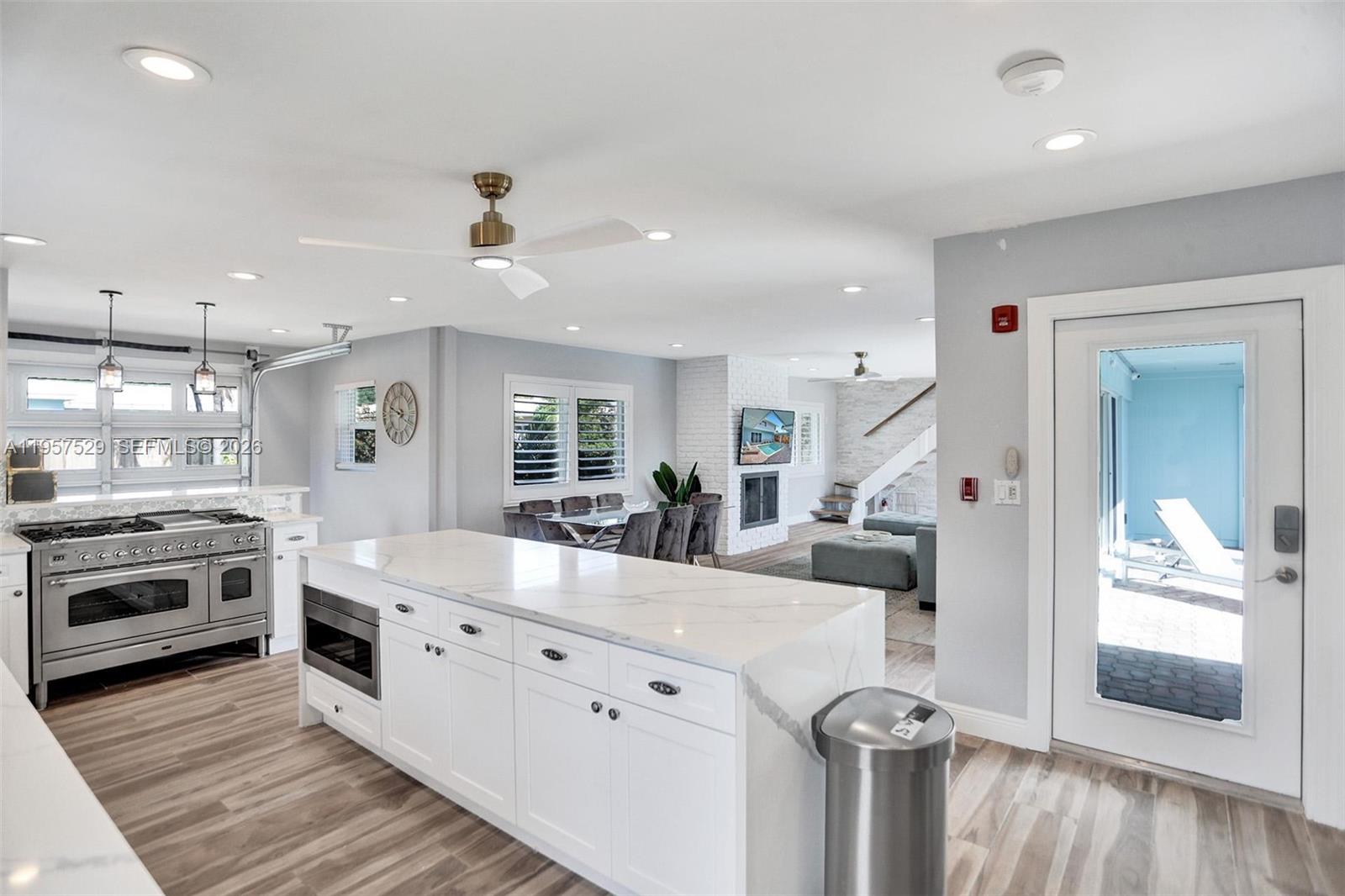 A modern kitchen features a white marble island, stainless steel appliances, and light wood flooring — 1341 SE 7th Ave, Pompano Beach FL 33060, POMPANO BEACH, FL