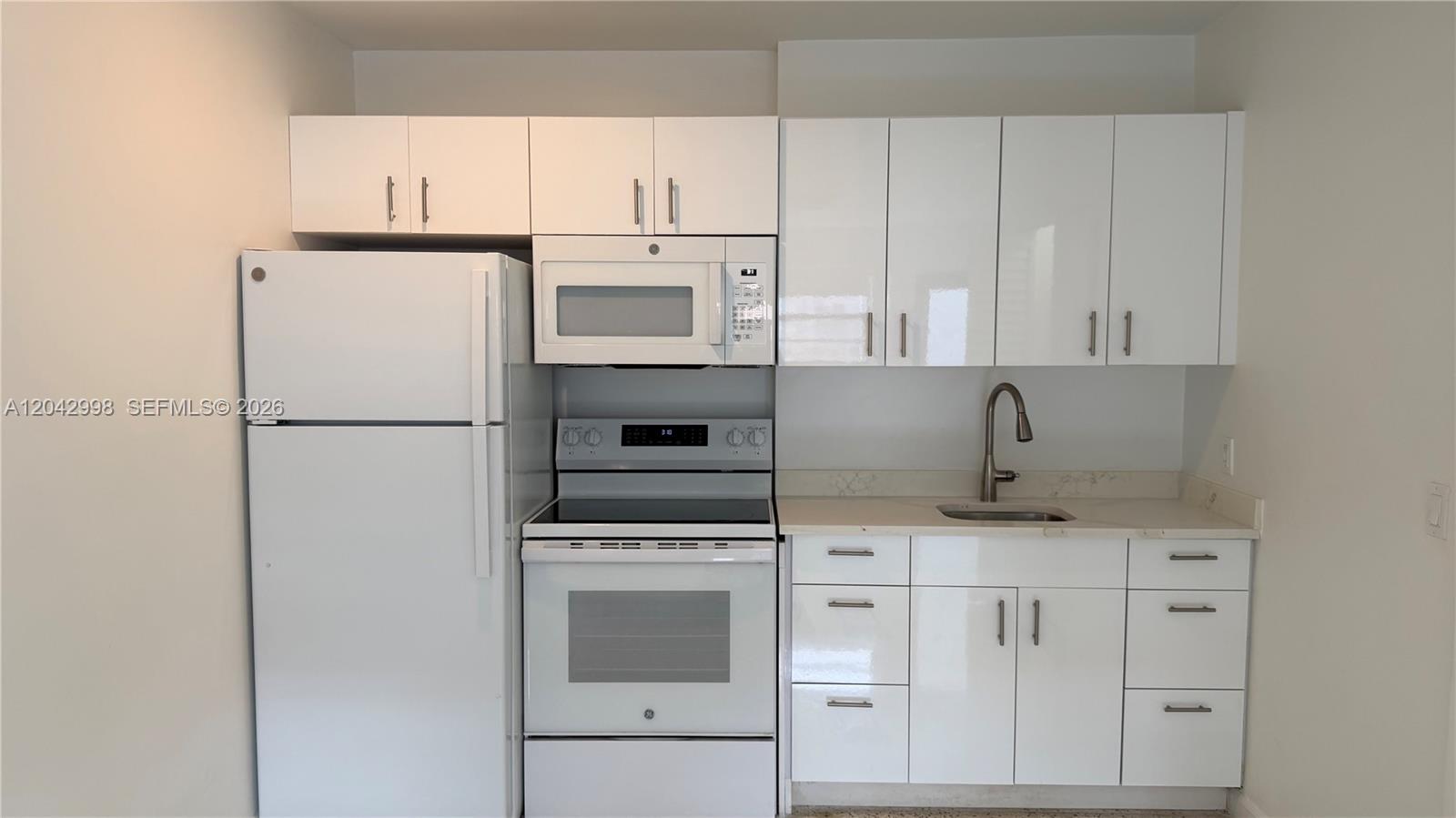 A compact kitchen features white cabinets, white appliances, and a stainless steel faucet — 612 NW 43rd Ct # 0, Miami FL 33126, MIAMI, FL