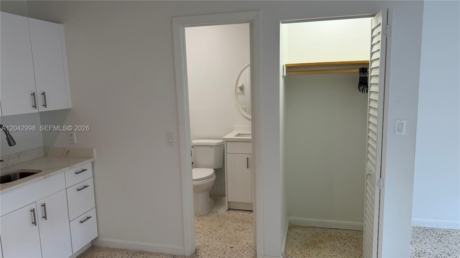A kitchen area features white cabinets next to a bathroom doorway and a closet — 612 NW 43rd Ct # 0, Miami FL 33126, MIAMI, FL