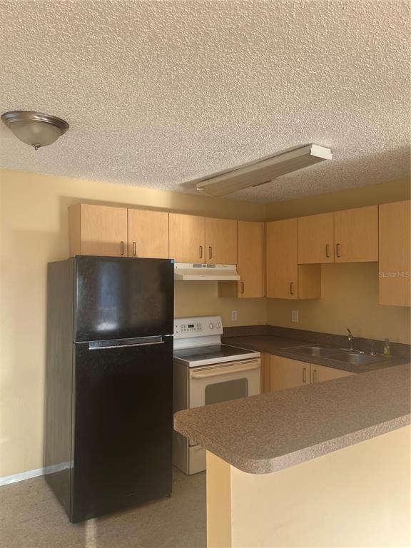 A kitchen features light wood cabinets, a black refrigerator, a white stove, and laminate countertops — 800 N FISKE BOULEVARD UNIT 711, COCOA, FL