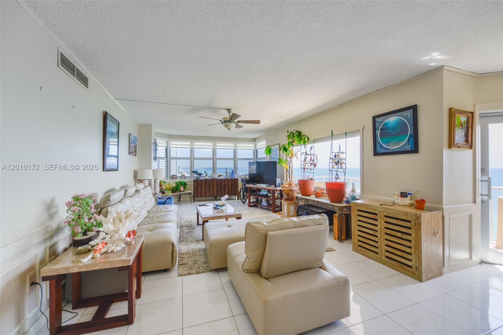 A living room with white tile floors, a beige sofa, and large ocean-view windows — 1950 S Ocean Dr # 15P, Hallandale Beach FL 33009, HALLANDALE BEACH, FL