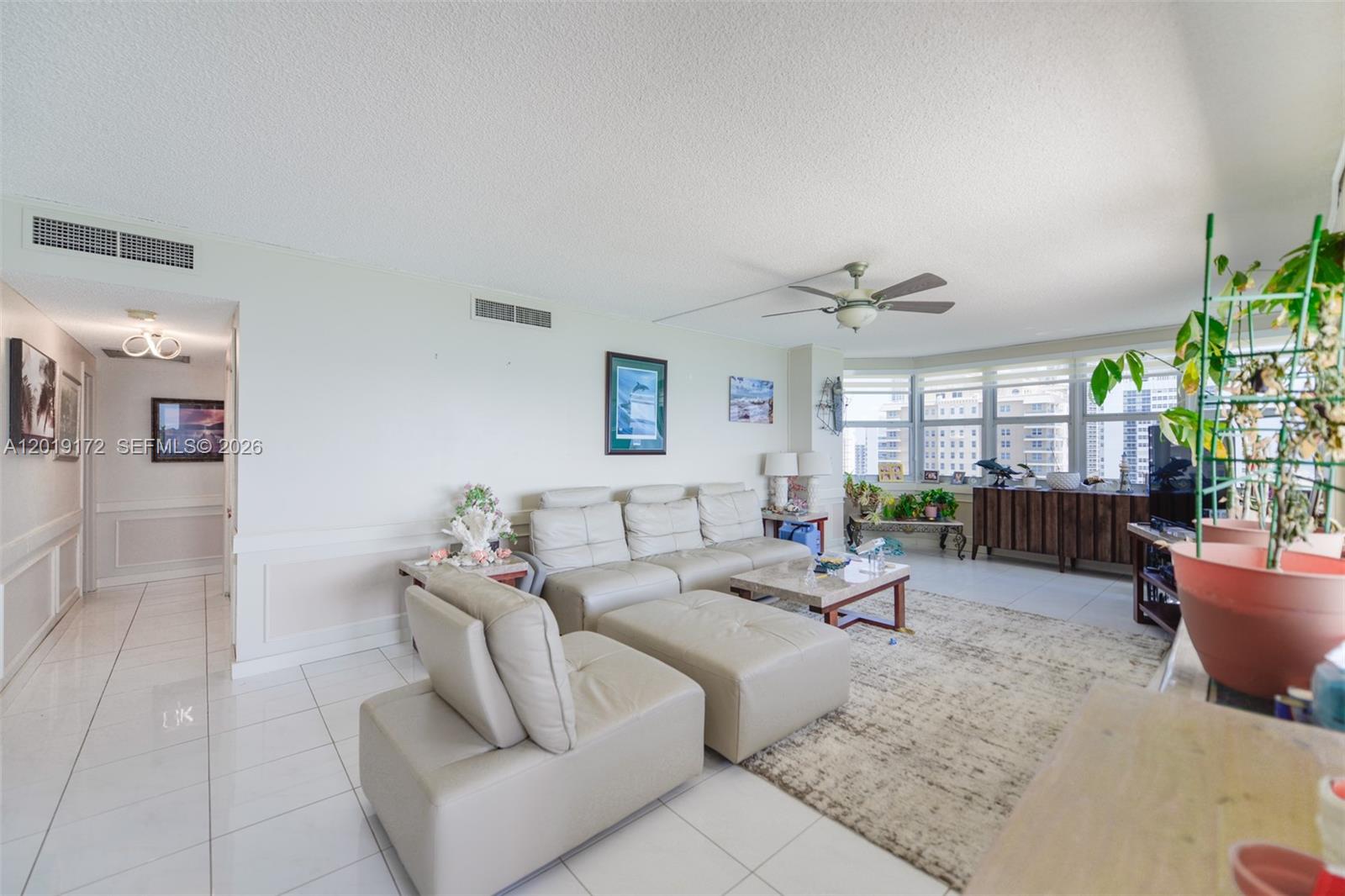 A living room features white tile flooring, a beige sectional sofa, and floor-to-ceiling windows — 1950 S Ocean Dr # 15P, Hallandale Beach FL 33009, HALLANDALE BEACH, FL
