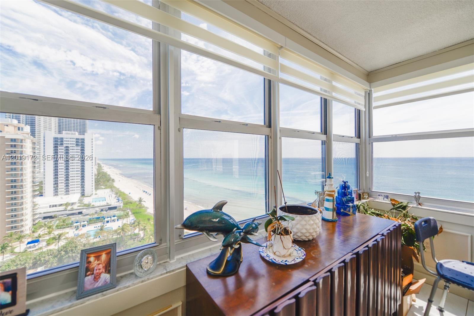 A sunroom features a wooden cabinet, decorative items, and a panoramic view of the ocean — 1950 S Ocean Dr # 15P, Hallandale Beach FL 33009, HALLANDALE BEACH, FL