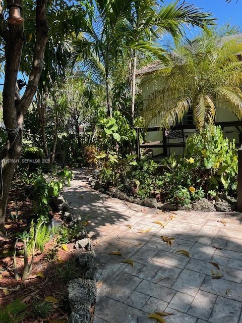 A stone walkway leads through a lush garden toward a yellow building with a porch — 410 NW 31st St, Miami FL 33127, MIAMI, FL