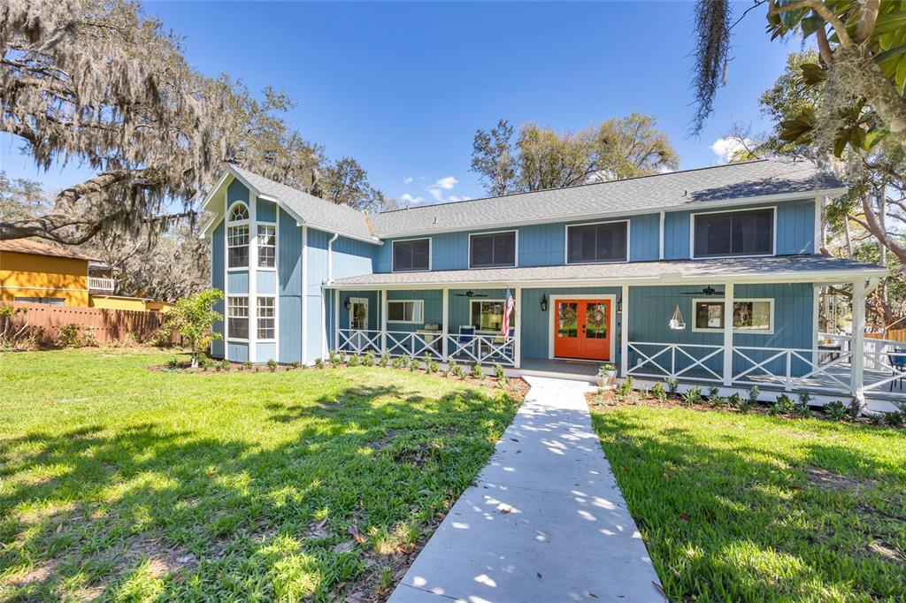 A grassy backyard with Adirondack chairs faces a lake behind a black metal fence — 1217 EDGEWOOD RANCH ROAD, ORLANDO, FL
