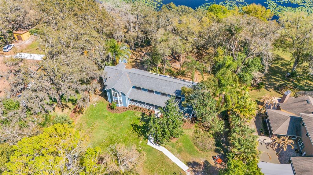 An aerial view shows a blue two-story house surrounded by trees near a lake — 1217 EDGEWOOD RANCH ROAD, ORLANDO, FL