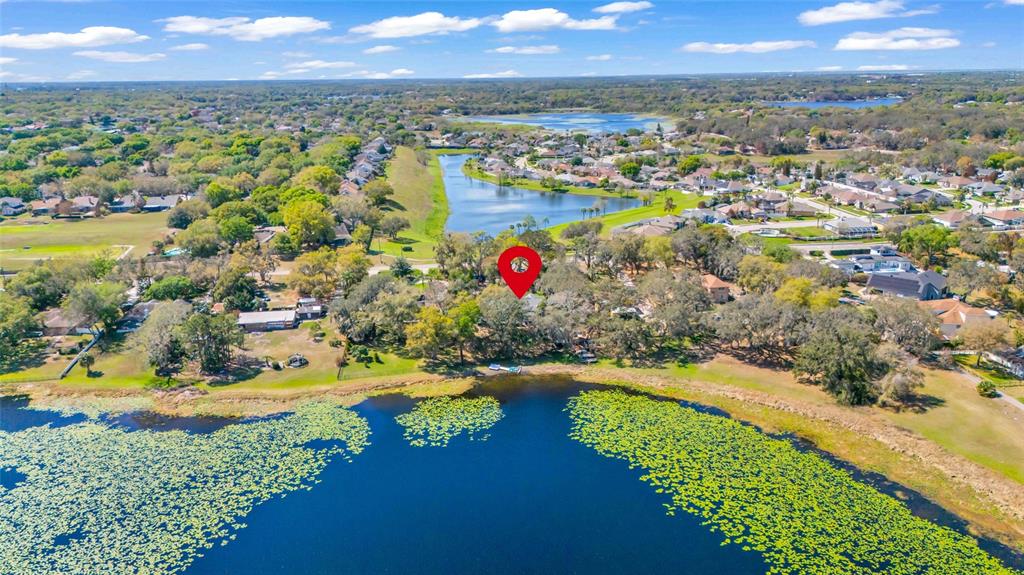 An aerial view shows a house marked by a red pin beside a lake — 1217 EDGEWOOD RANCH ROAD, ORLANDO, FL