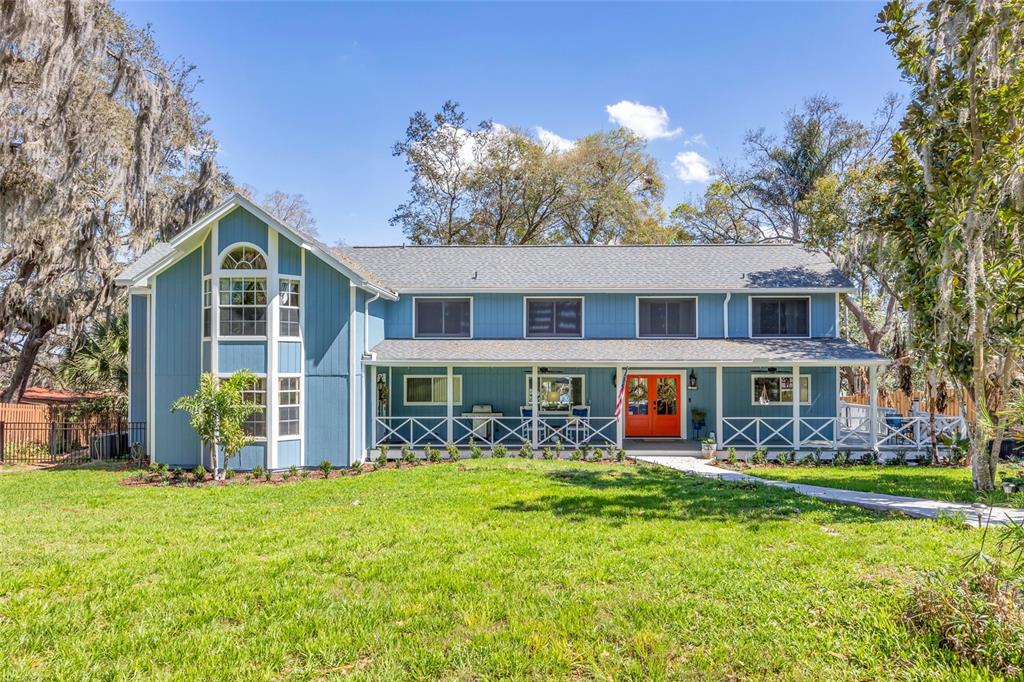 A two-story blue house with a wrap-around porch and a bright orange front door — 1217 EDGEWOOD RANCH ROAD, ORLANDO, FL