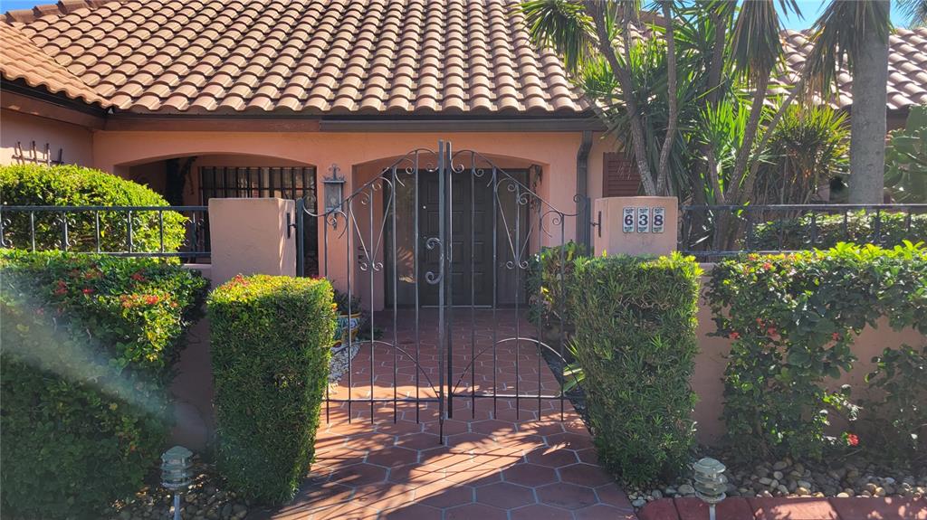 A gated walkway leads to the front entrance of a house with a tiled roof — 638 S OWL DRIVE, SARASOTA, FL