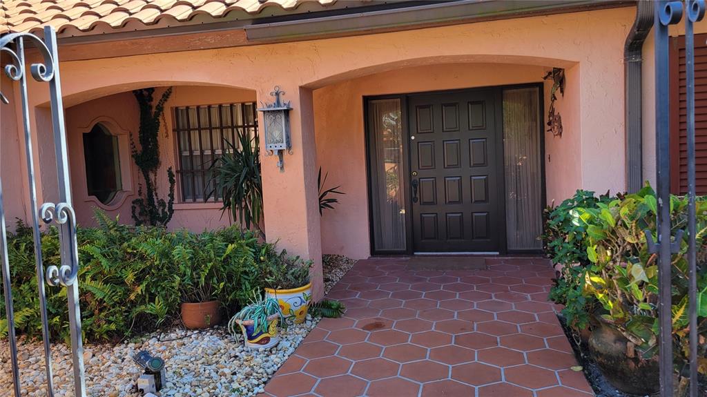 A pink stucco house features a tiled walkway leading to a dark brown front door — 638 S OWL DRIVE, SARASOTA, FL