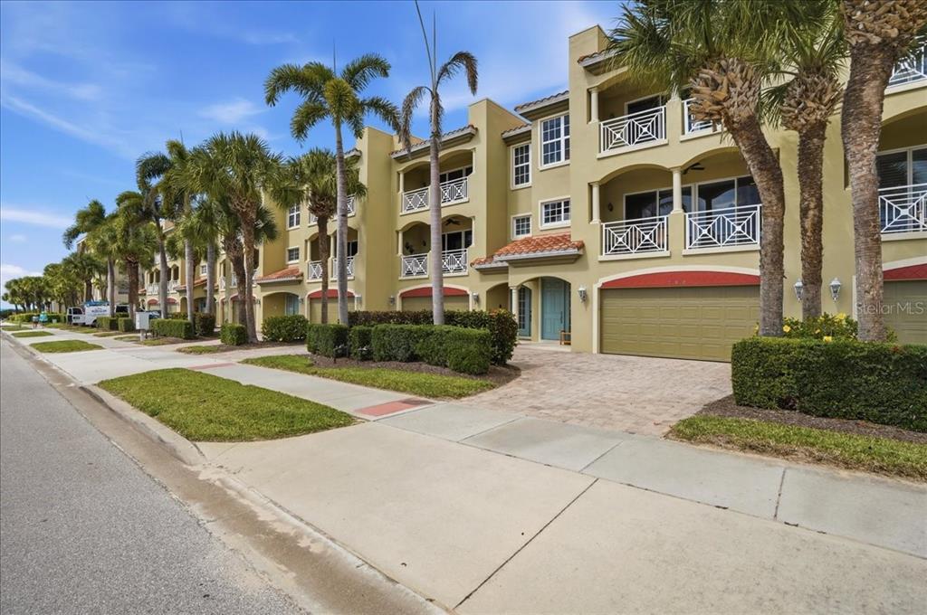 A multi-story tan apartment building with palm trees and a paved driveway — 702 GRANADA AVENUE UNIT 7, VENICE, FL