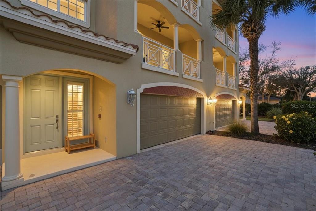 Exterior view of a multi-story building with a paved driveway, garage, and front entrance — 702 GRANADA AVENUE UNIT 7, VENICE, FL