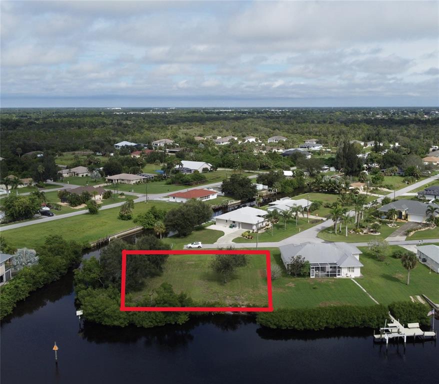 An aerial view shows a vacant waterfront lot outlined in red next to a house — 3690 PEACE RIVER DRIVE, PUNTA GORDA, FL