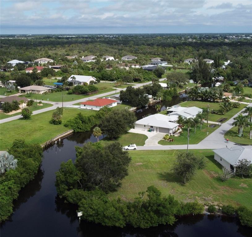 An aerial view shows houses situated along a canal in a suburban neighborhood — 3690 PEACE RIVER DRIVE, PUNTA GORDA, FL