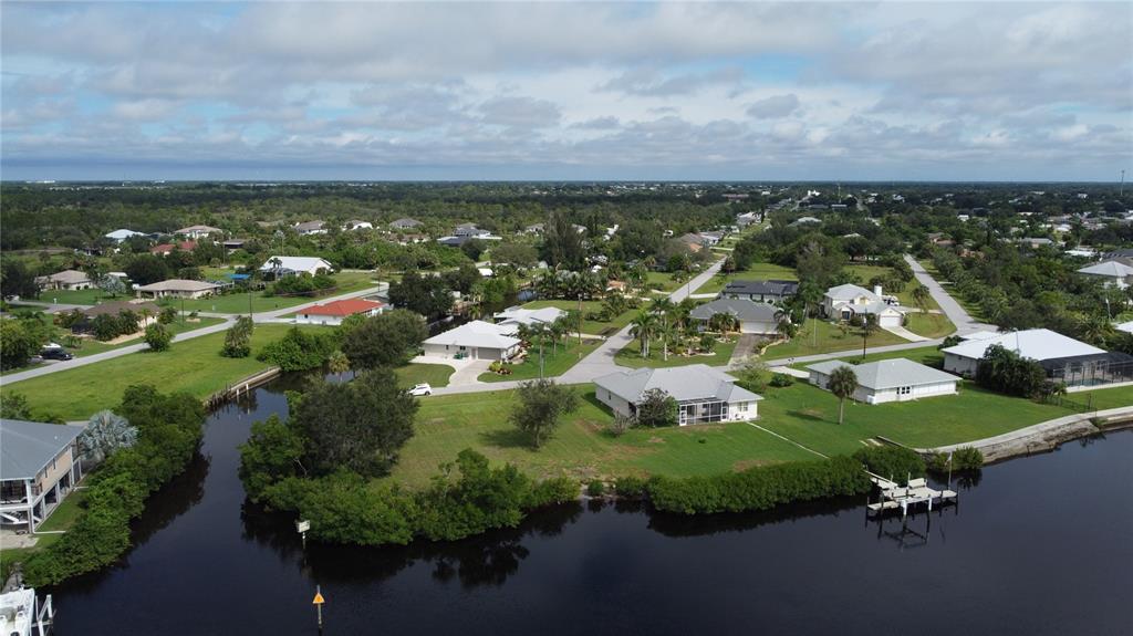 An aerial view shows houses with green lawns situated along a canal with mangroves — 3690 PEACE RIVER DRIVE, PUNTA GORDA, FL