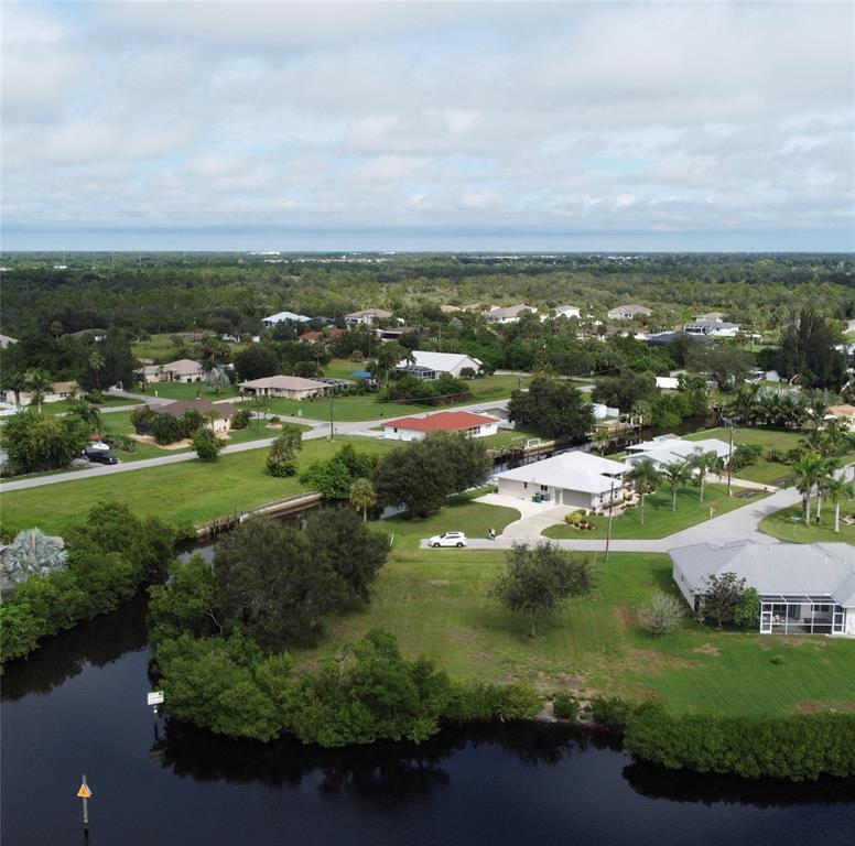 An aerial view shows houses situated along a canal surrounded by trees and green lawns — 3690 PEACE RIVER DRIVE, PUNTA GORDA, FL