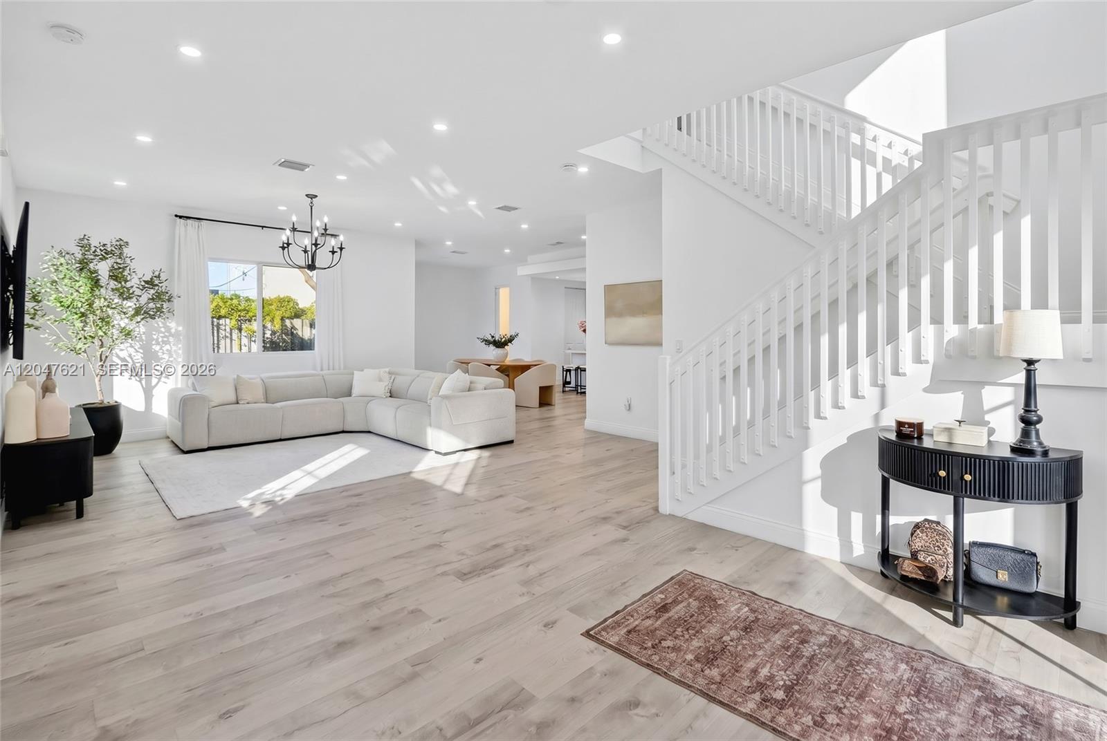 A bright, open-concept living room features light wood flooring, a white sectional, and a staircase — 17901 SW 152nd Ave, Miami FL 33187, MIAMI, FL