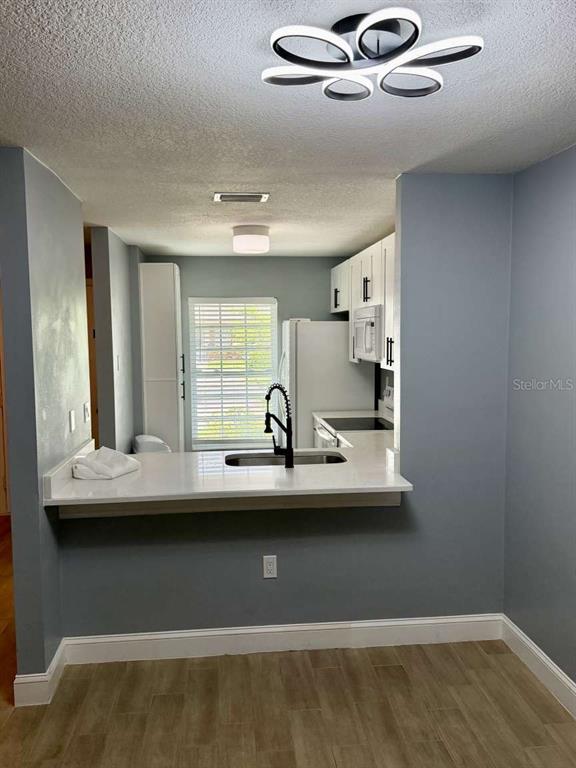 A kitchen with white cabinets, a quartz countertop, and a breakfast bar overlooks a room — 2852 STILWELL COURT, NEW PORT RICHEY, FL