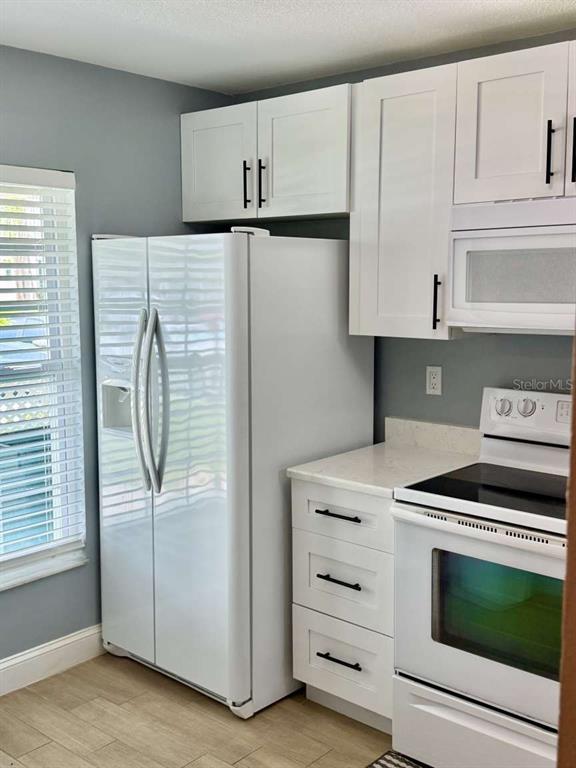 A kitchen features white cabinets, a white refrigerator, and a white stove with a microwave — 2852 STILWELL COURT, NEW PORT RICHEY, FL