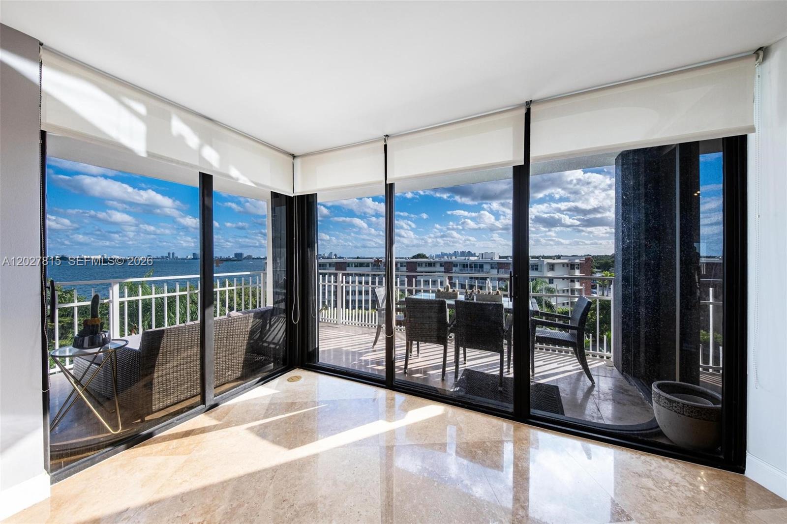 A room with marble floors and floor-to-ceiling windows opens onto a balcony overlooking water — 4000 Towerside Ter # 604, Miami FL 33138, MIAMI, FL