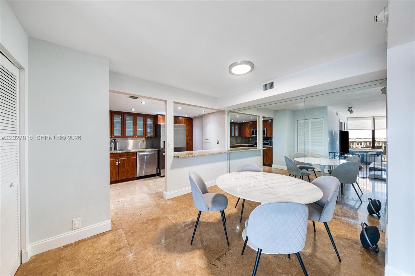 A dining area with a marble table and chairs sits adjacent to a kitchen — 4000 Towerside Ter # 604, Miami FL 33138, MIAMI, FL