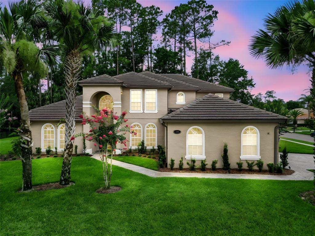 A two-story tan stucco house with a tiled roof and arched windows sits on grass — 1613 SHADOWMOSS CIRCLE, LAKE MARY, FL