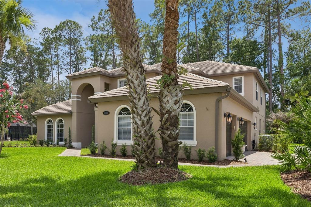 A two-story tan stucco house with a tiled roof, arched windows, and a paved driveway — 1613 SHADOWMOSS CIRCLE, LAKE MARY, FL