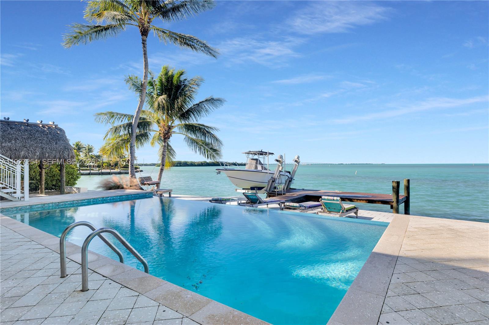 An infinity pool overlooks a boat docked at a pier by the ocean — 166 Bayview Drive, Islamorada FL 33036, ISLAMORADA, FL