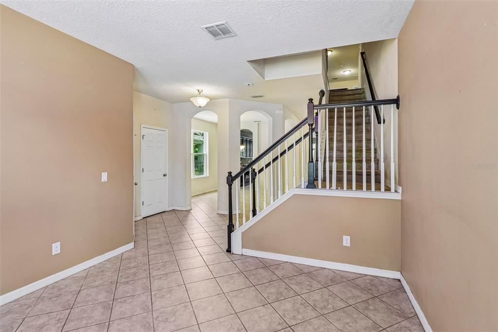 An entryway features tiled flooring, a staircase with a dark railing, and arched doorways — 5231 VILLA ROSA AVENUE, ST CLOUD, FL