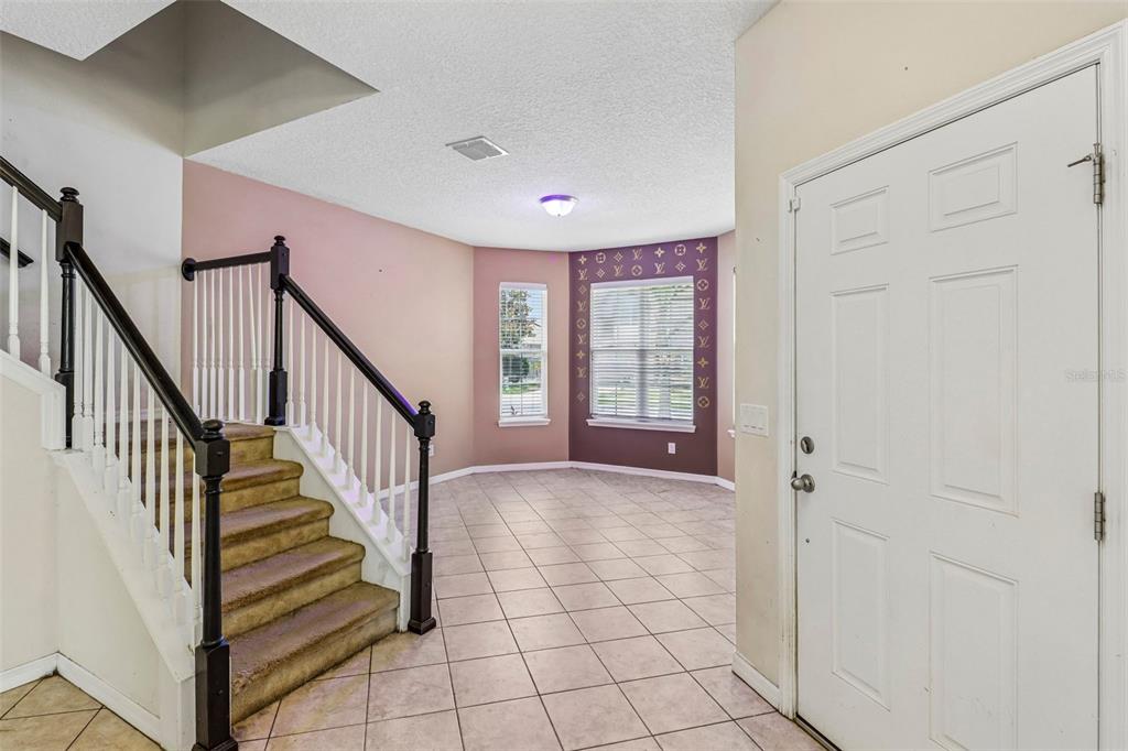 An entryway features a carpeted staircase, tiled floors, and a wall with a designer logo pattern — 5231 VILLA ROSA AVENUE, ST CLOUD, FL