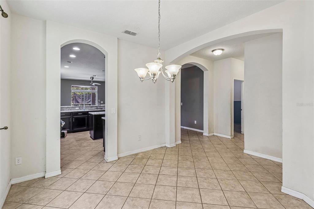 A dining area with tile flooring, a chandelier, and arched doorways leading to other rooms — 5231 VILLA ROSA AVENUE, ST CLOUD, FL