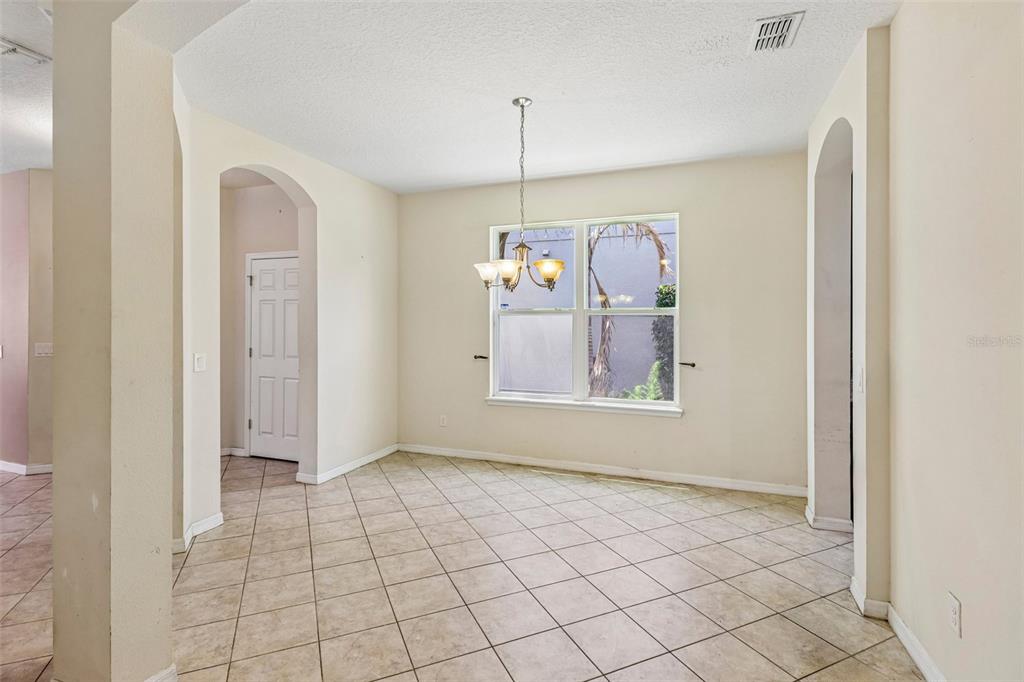 A dining room with beige walls, tile flooring, a chandelier, and a large window — 5231 VILLA ROSA AVENUE, ST CLOUD, FL
