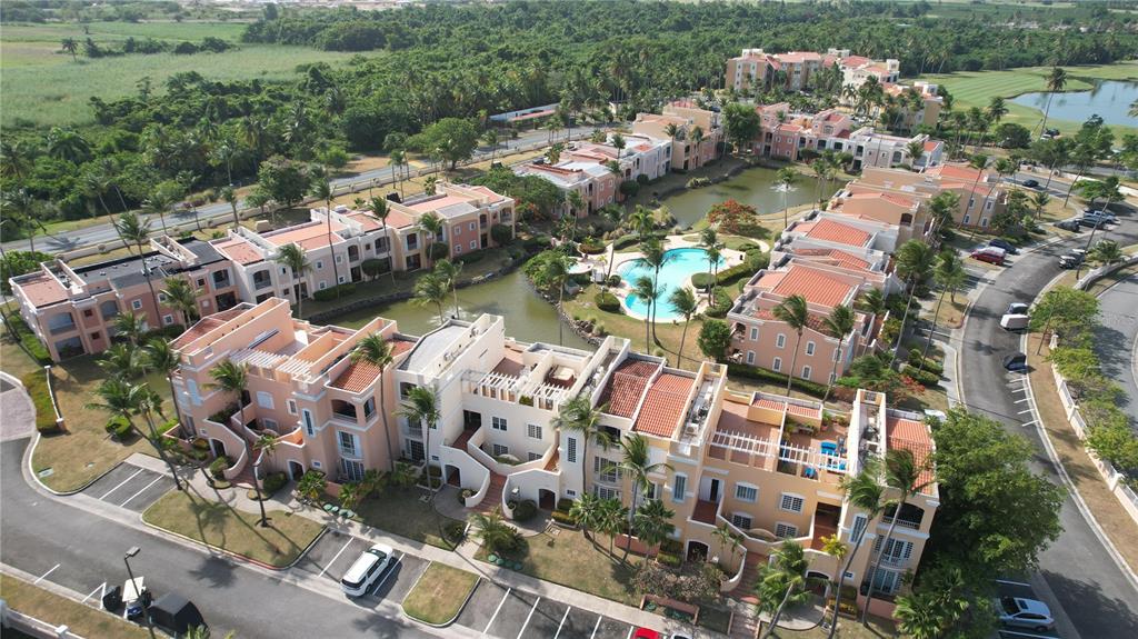 An aerial view shows a residential complex with peach-colored buildings, a swimming pool, and ponds — Candelero Drive SE FAIRWAY COURTS - PALMAS DEL MAR COURTS N UNIT 734, HUMACAO, PR