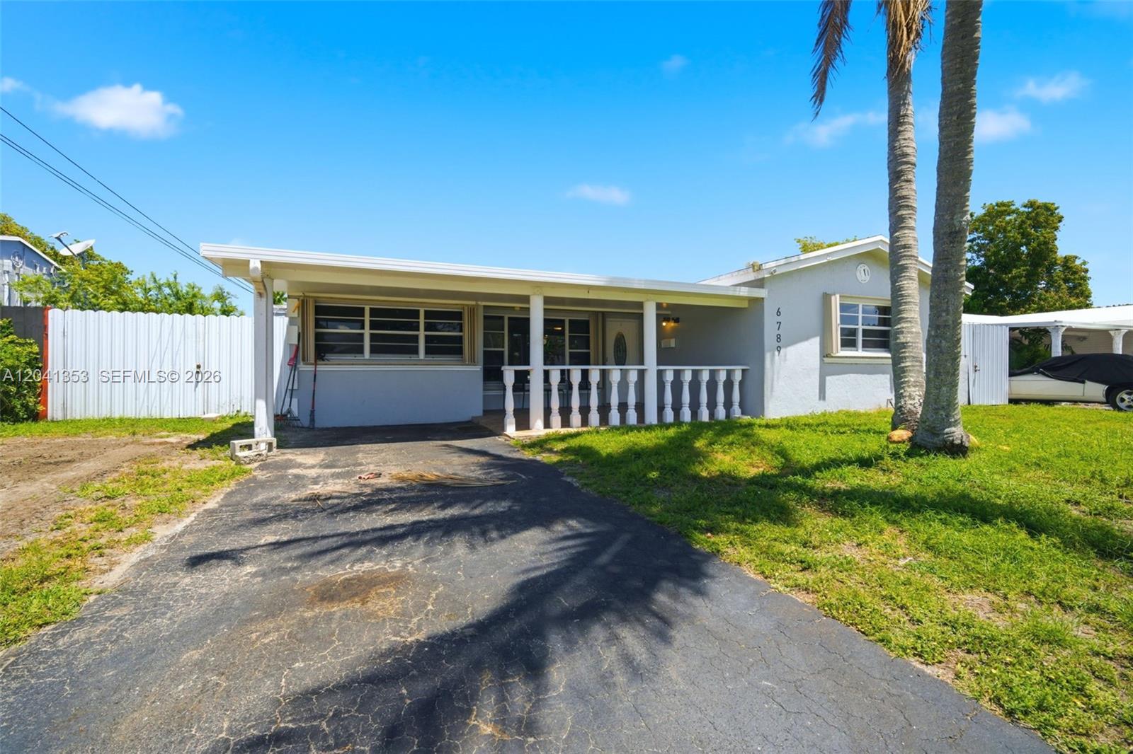 A single-story house features a covered front porch with white balusters and a paved driveway — 6789 SW 27th Ct, Miramar FL 33023, MIRAMAR, FL