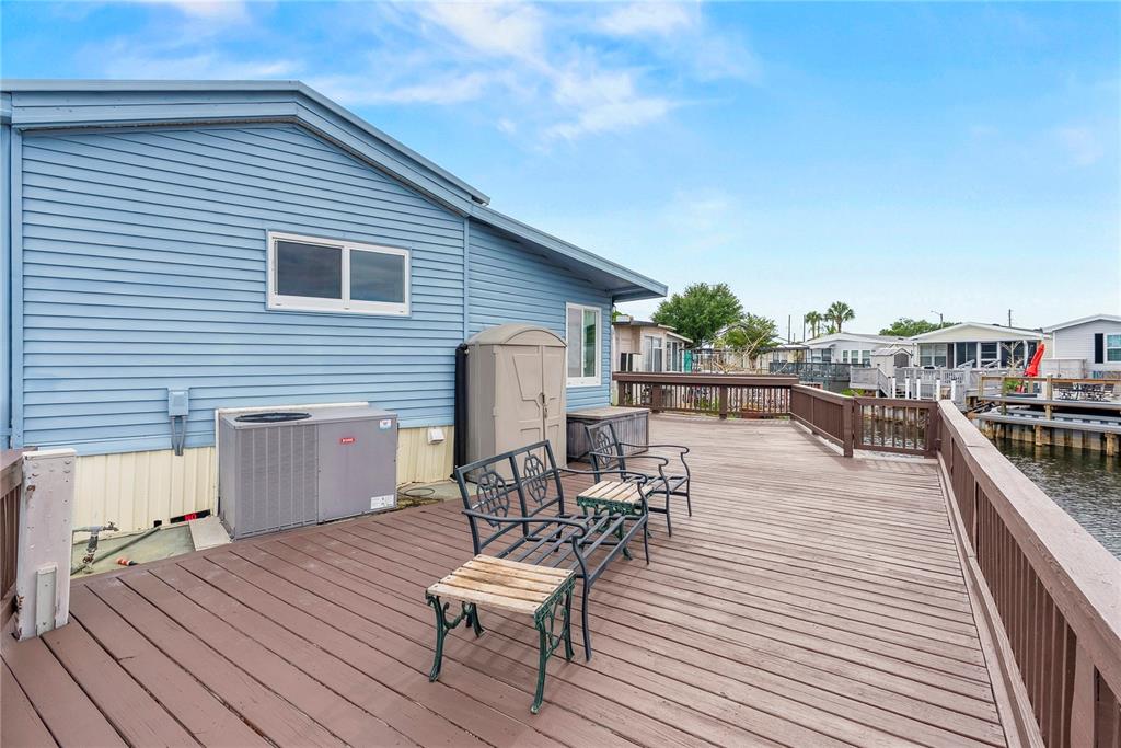 A blue mobile home features a large wooden deck overlooking a canal with boat docks — 9000 US HIGHWAY 192 UNIT 211, CLERMONT, FL