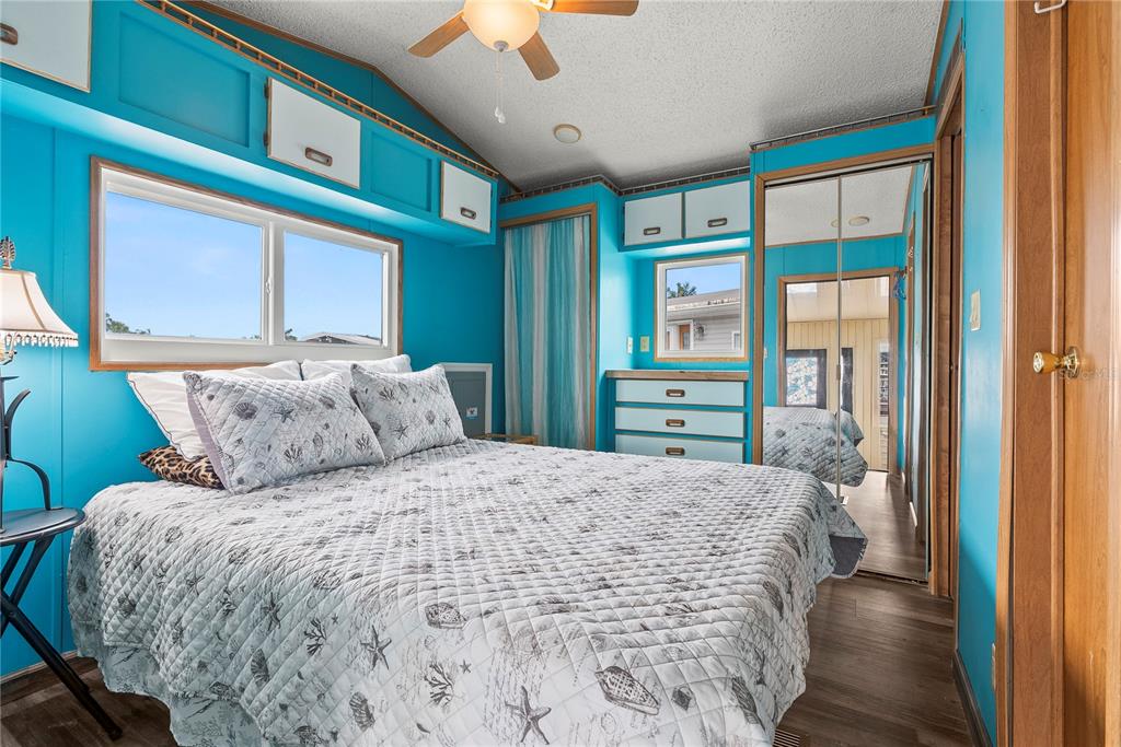 A bedroom with bright blue walls, a queen bed, built-in cabinetry, and mirrored closet doors — 9000 US HIGHWAY 192 UNIT 211, CLERMONT, FL