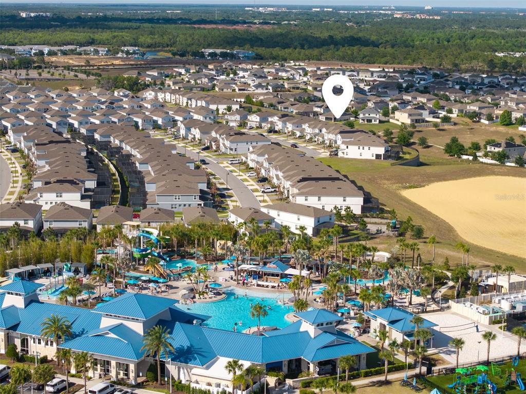 An aerial view shows a residential neighborhood with a large community pool and clubhouse — 1721 KONA LANE LANE, DAVENPORT, FL