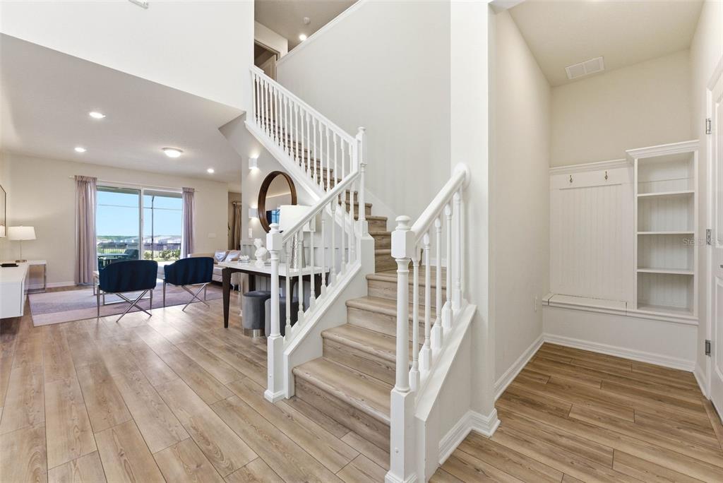 A foyer with a built-in mudroom bench, wood-look flooring, and a staircase leading upstairs — 1721 KONA LANE LANE, DAVENPORT, FL