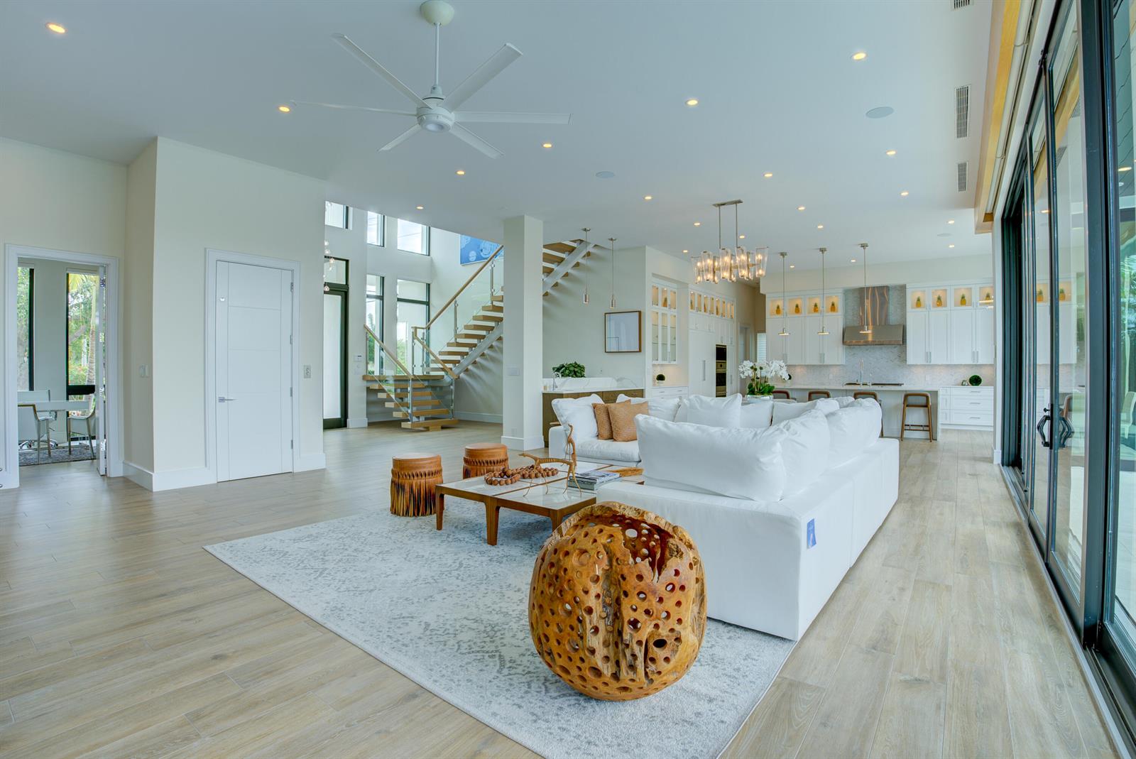 A spacious open-concept living room features a white sectional sofa, wood flooring, and a staircase — 2801 NE 36th Street, Lighthouse Point FL 33064, LIGHTHOUSE POINT, FL