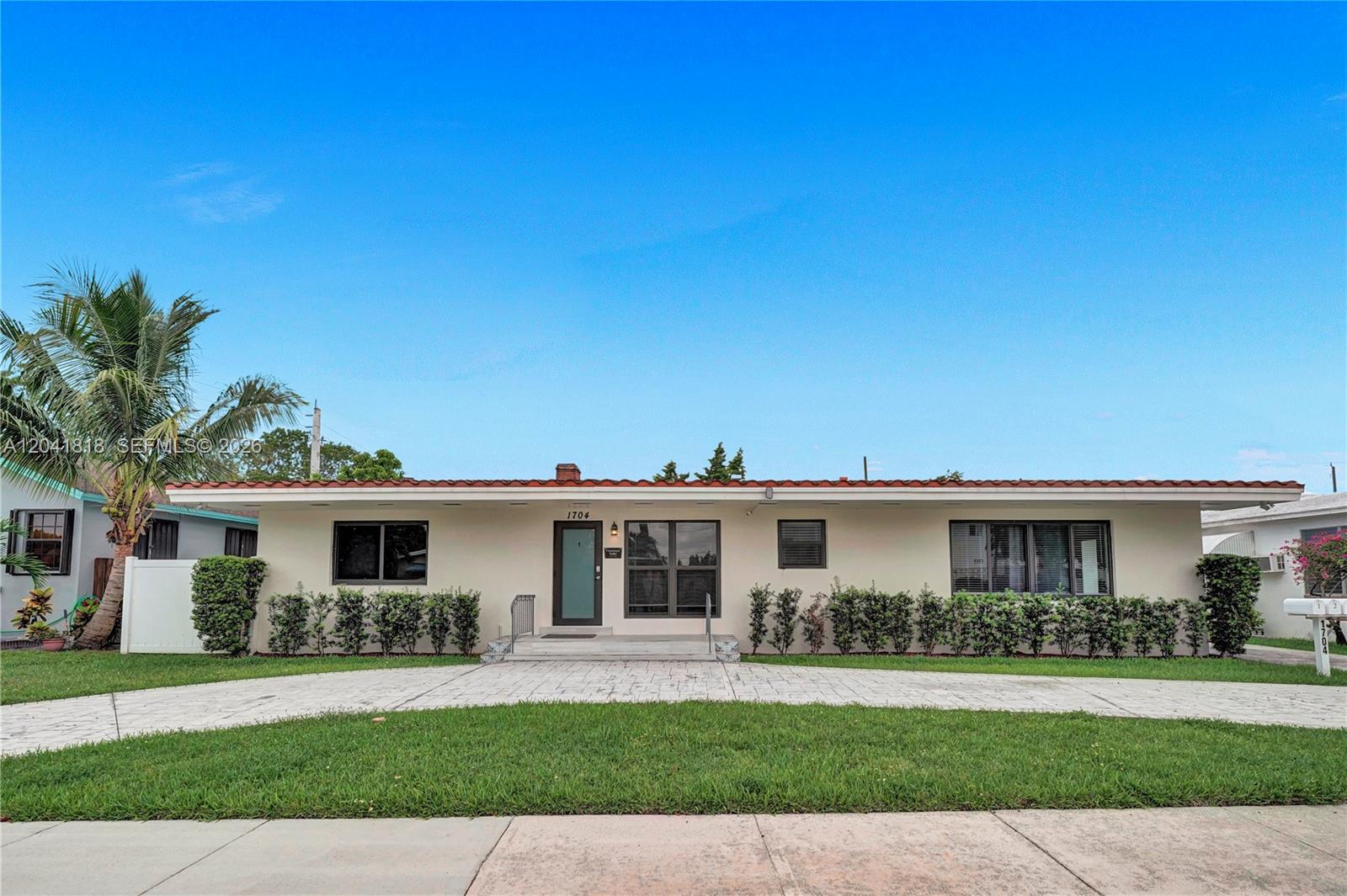 A single-story house with a light-colored exterior, a red tile roof, and a paved driveway — 1704 Rodman St, Hollywood FL 33020, HOLLYWOOD, FL