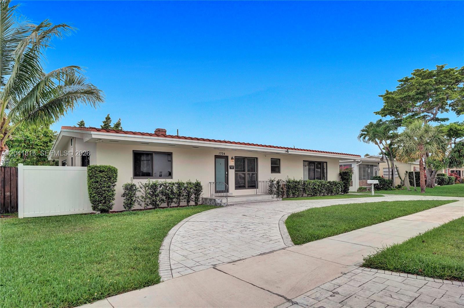 A single-story house with a tiled roof, white stucco walls, and a paved driveway — 1704 Rodman St, Hollywood FL 33020, HOLLYWOOD, FL