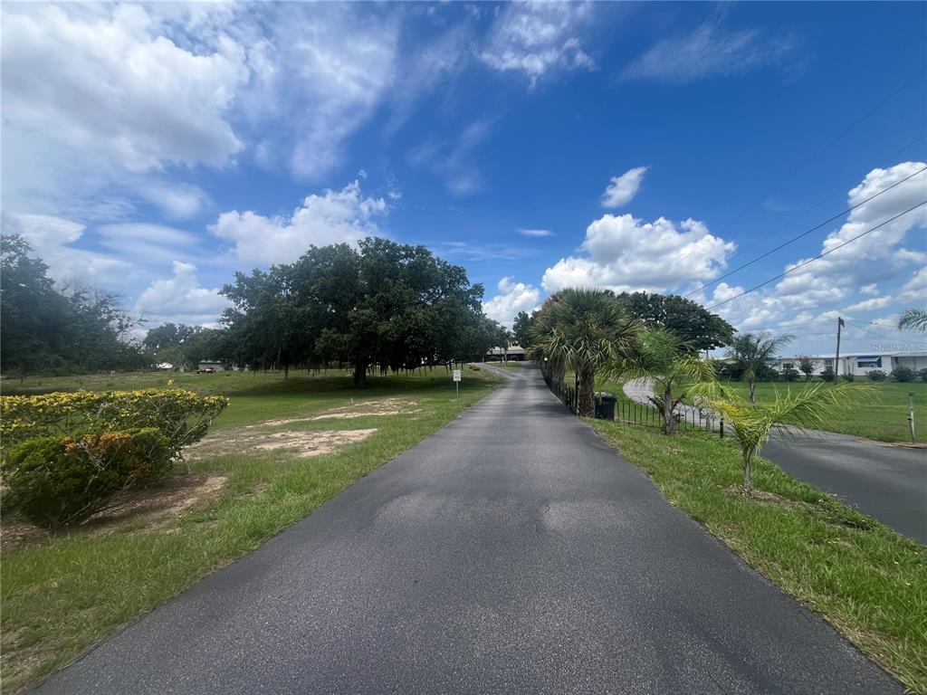 A paved driveway leads toward a house surrounded by trees and a grassy lawn — 1145 S LAKE REEDY BOULEVARD, FROSTPROOF, FL