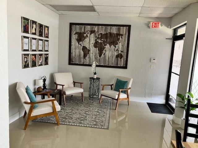 A waiting room features two armchairs, a patterned rug, and a large world map wall art — 290 SW 12th Avenue, Pompano Beach FL 33069, POMPANO BEACH, FL