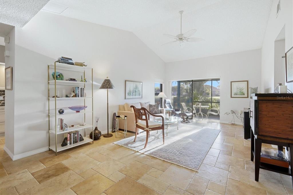 A living room features vaulted ceilings, tile flooring, a bookshelf, and a sliding glass door — 260 SOUTHAMPTON DRIVE UNIT 312, VENICE, FL