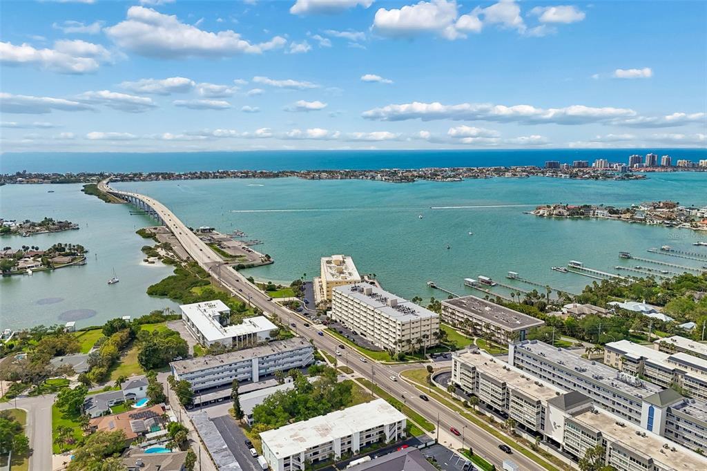 An aerial view shows a bridge crossing a bay with surrounding residential buildings and water — 2944 W BAY DRIVE UNIT 106, BELLEAIR BLUFFS, FL