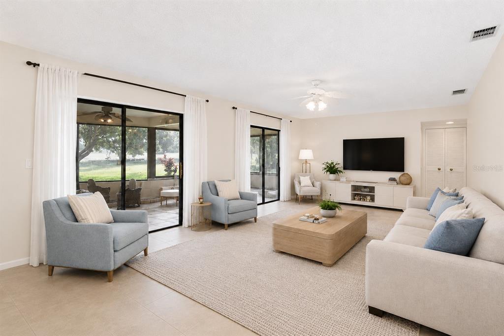 A living room with light-colored furniture, a large area rug, and sliding glass doors — 2721 NORTHRIDGE DRIVE E, CLEARWATER, FL