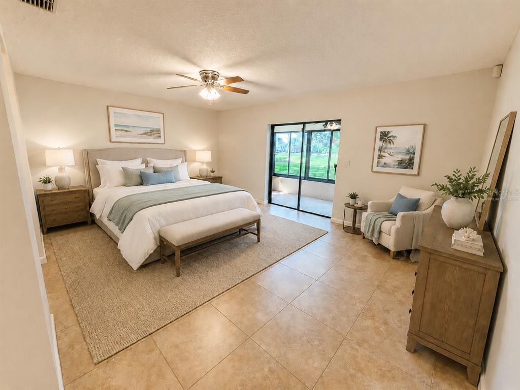 A bedroom features a king bed, tiled floors, a seating area, and sliding glass doors — 2721 NORTHRIDGE DRIVE E, CLEARWATER, FL