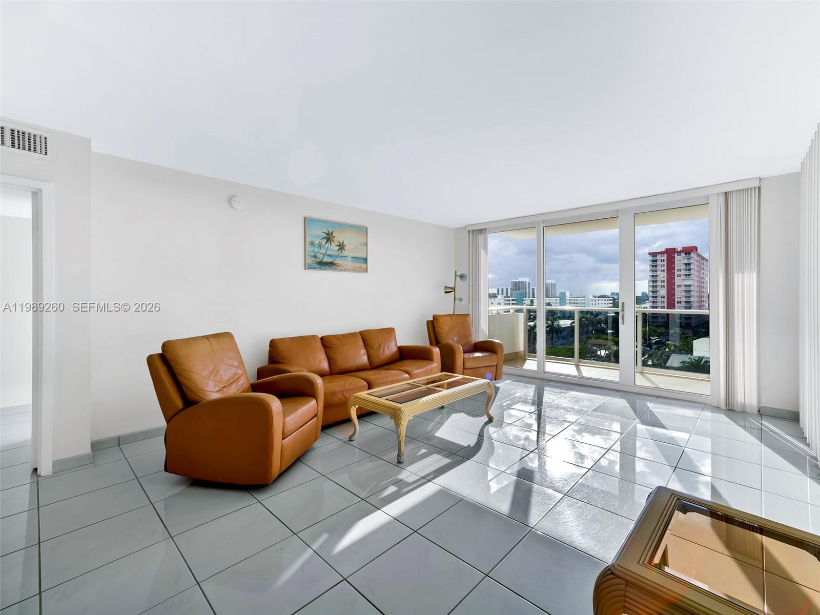 A living room features tan leather furniture, a glass-topped coffee table, and large balcony windows — 3140 S Ocean Dr # 612, Hallandale Beach FL 33009, HALLANDALE BEACH, FL
